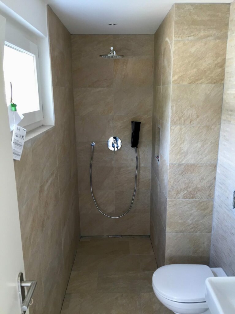 Bodenebene Dusche mit Rinne und grossformatigen Platten nach der Badsanierung