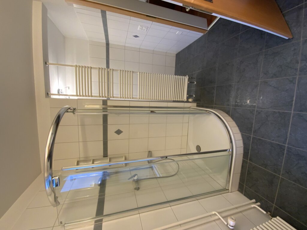 Altes Bad mit Runddusche, Duschwanne und weissen Wandfliesen