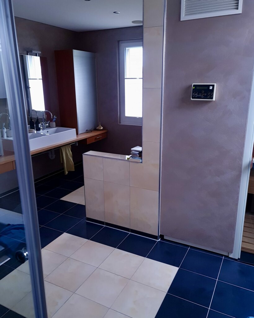 Badezimmer vor der Sanierung mit dunklen Bodenplatten