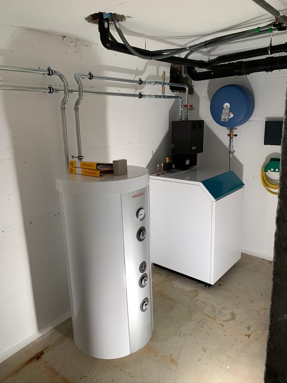 Neue Wärmepumpe mit Warmwasserspeicher im Keller eines Einfamilienhauses, Heizung sanieren